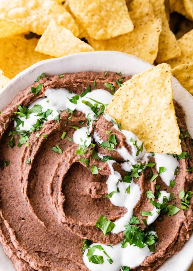 A chip resting in a bowl of black bean dip.