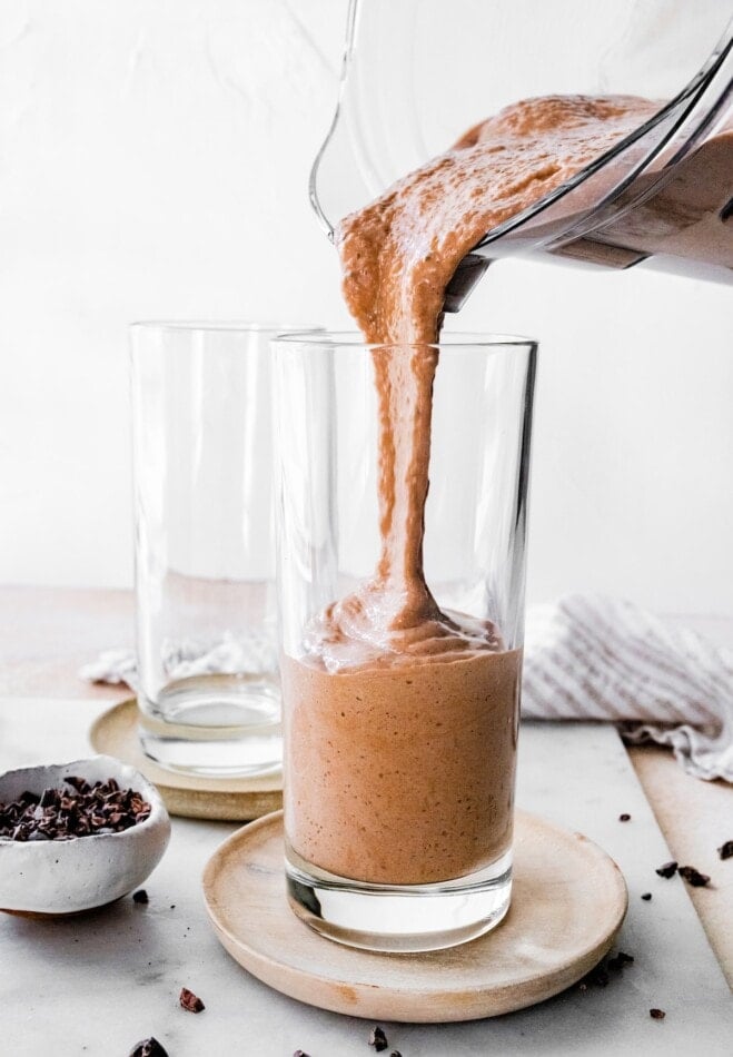 Pouring chocolate protein shake from a blender to a glass.