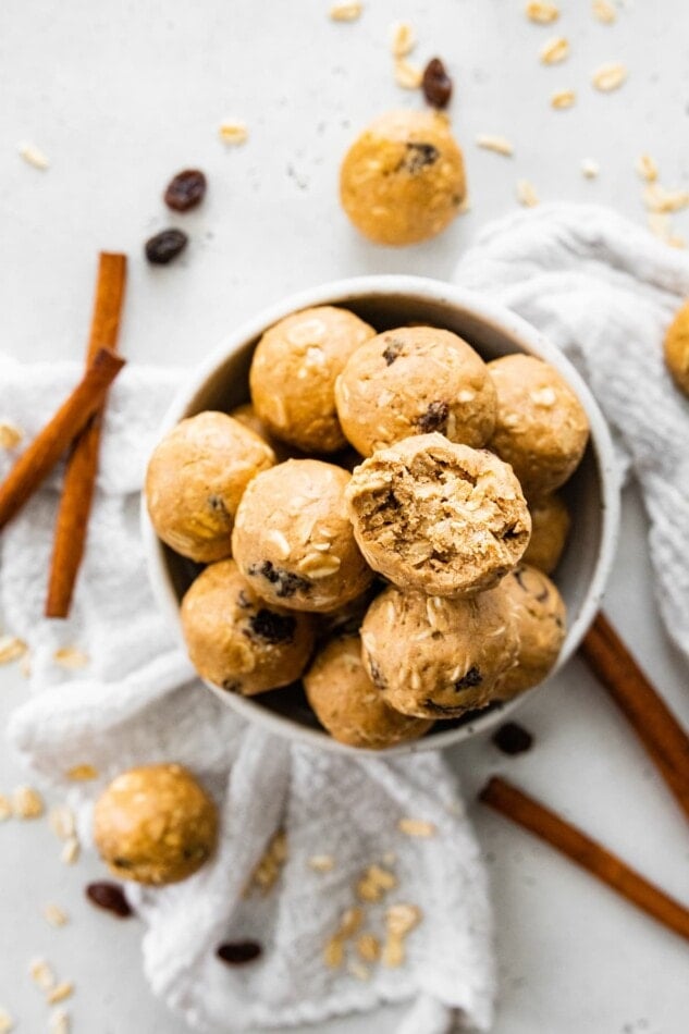 A bowl of protein balls, one of the balls has a bite taken out of it.