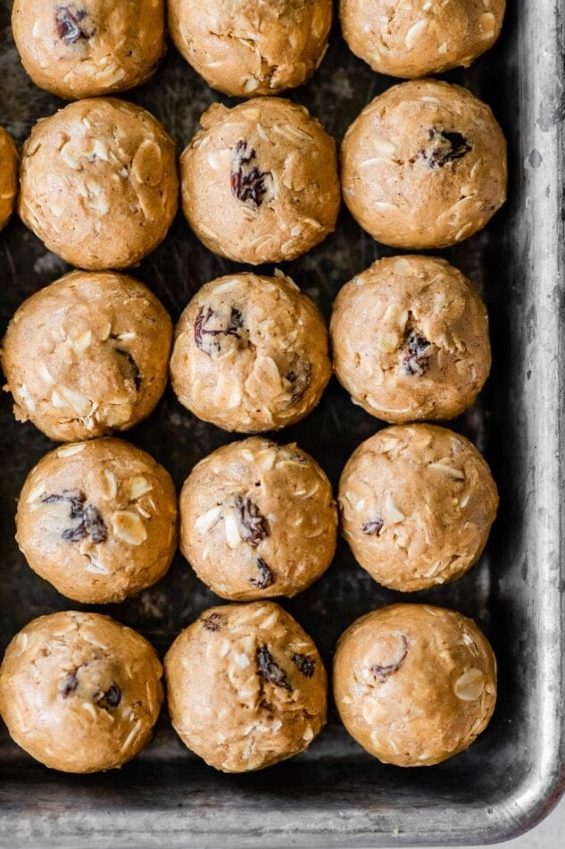 Cinnamon raisin protein balls lined up on a sheet pan.