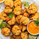 Air fried coconut shrimp on a plate with dipping sauce.