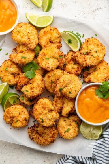 Air fried coconut shrimp on a plate with dipping sauce.