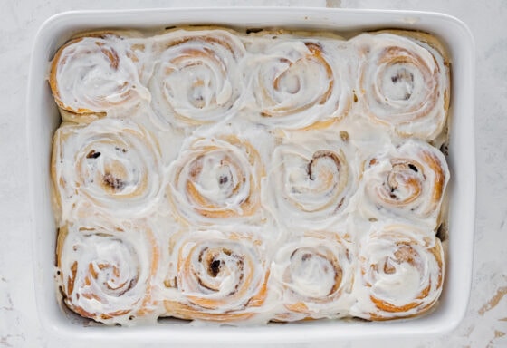 Iced fluffy cinnamon rolls in a baking dish.