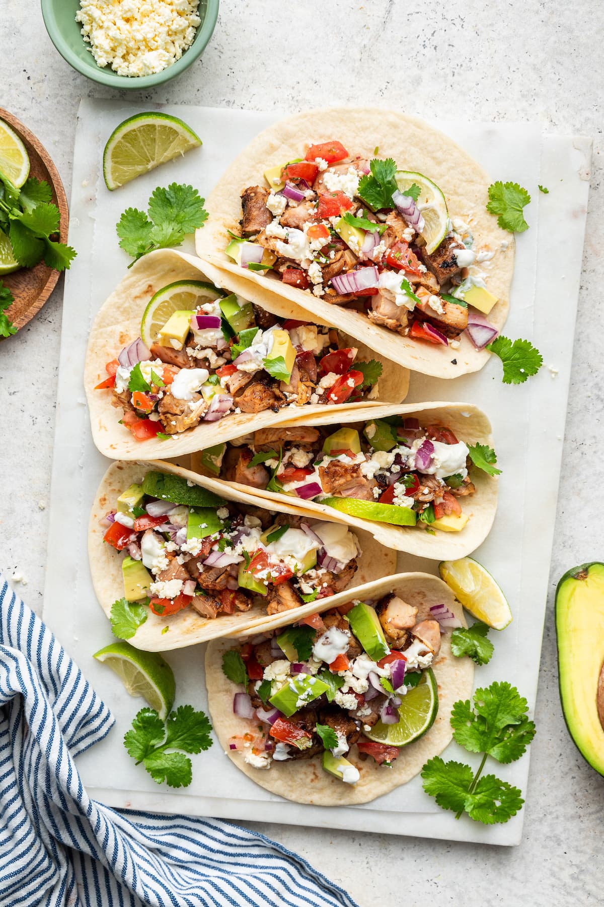 Chicken tacos in a row on a serving board.