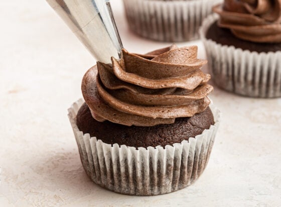 Icing a healthy chocolate cupcake with chocolate frosting.