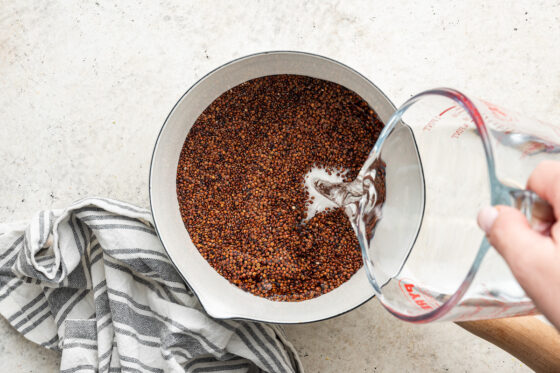 Adding water to a sauce pan with dry quinoa.