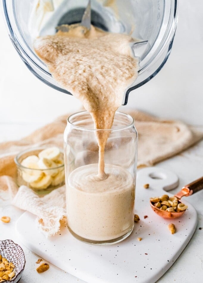 Pouring peanut butter protein shake from a blender to a glass.