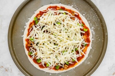 Toppings and cheese on top of pizza dough.