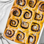 Vegan pumpkin cinnamon rolls in a baking dish.