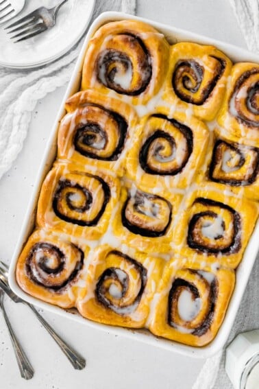 Vegan pumpkin cinnamon rolls in a baking dish.