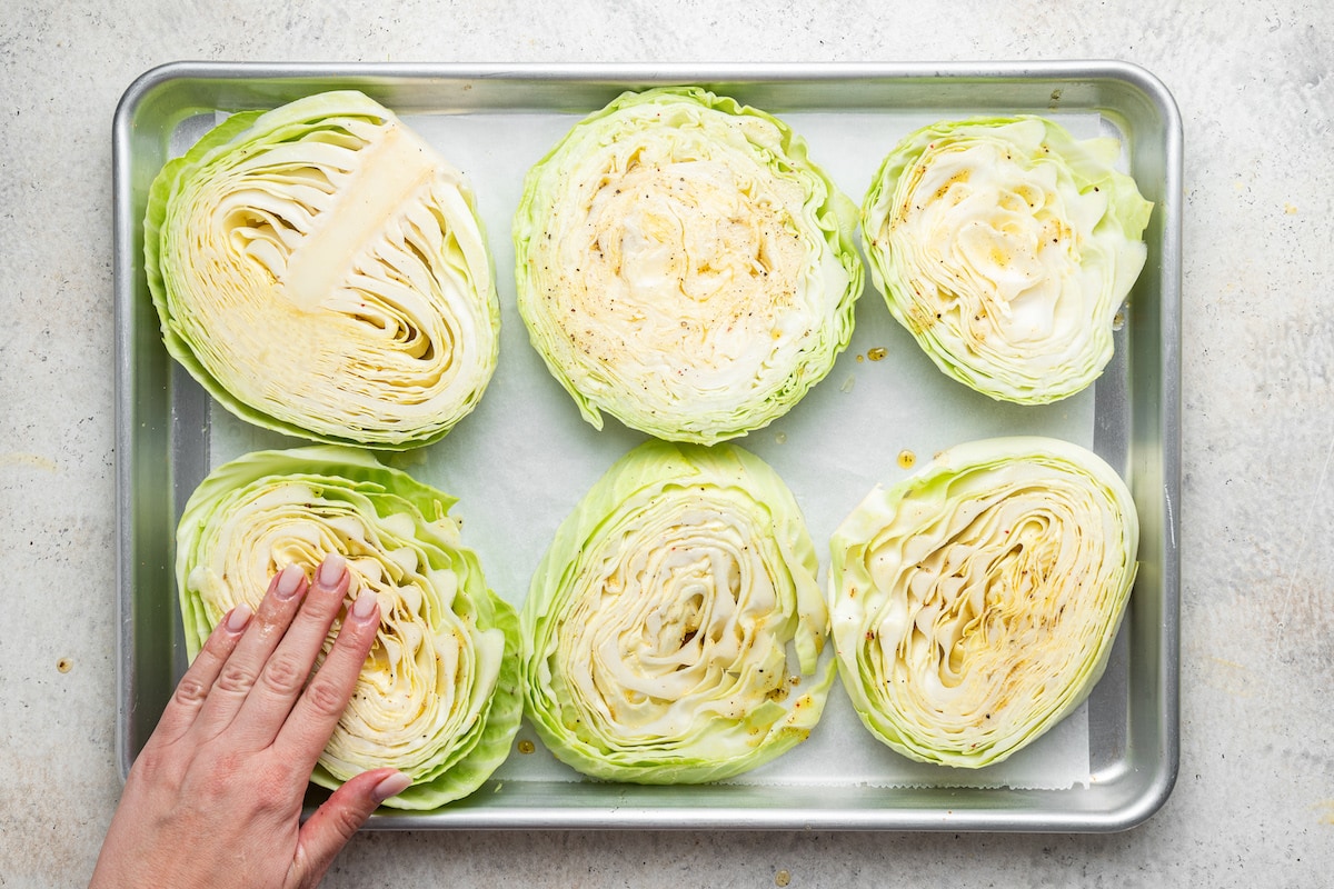 Massaging seasoning into cabbage steaks.
