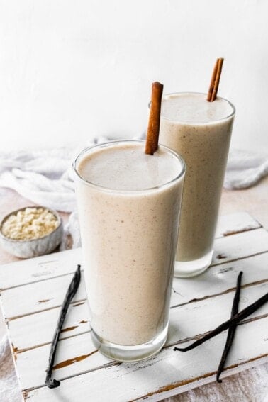 Two protein shakes with cinnamon sticks.