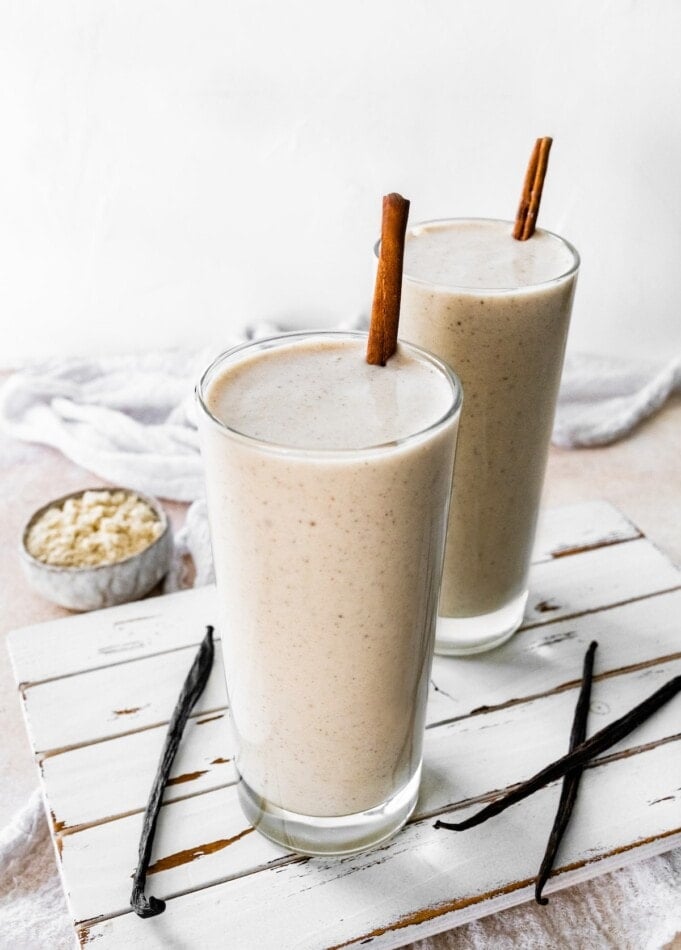 Two protein shakes with cinnamon sticks.