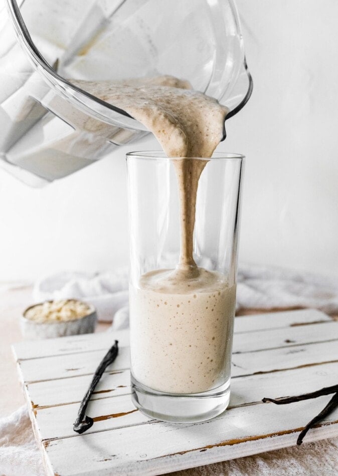 Pouring a vanilla protein shake from a blender into a glass.