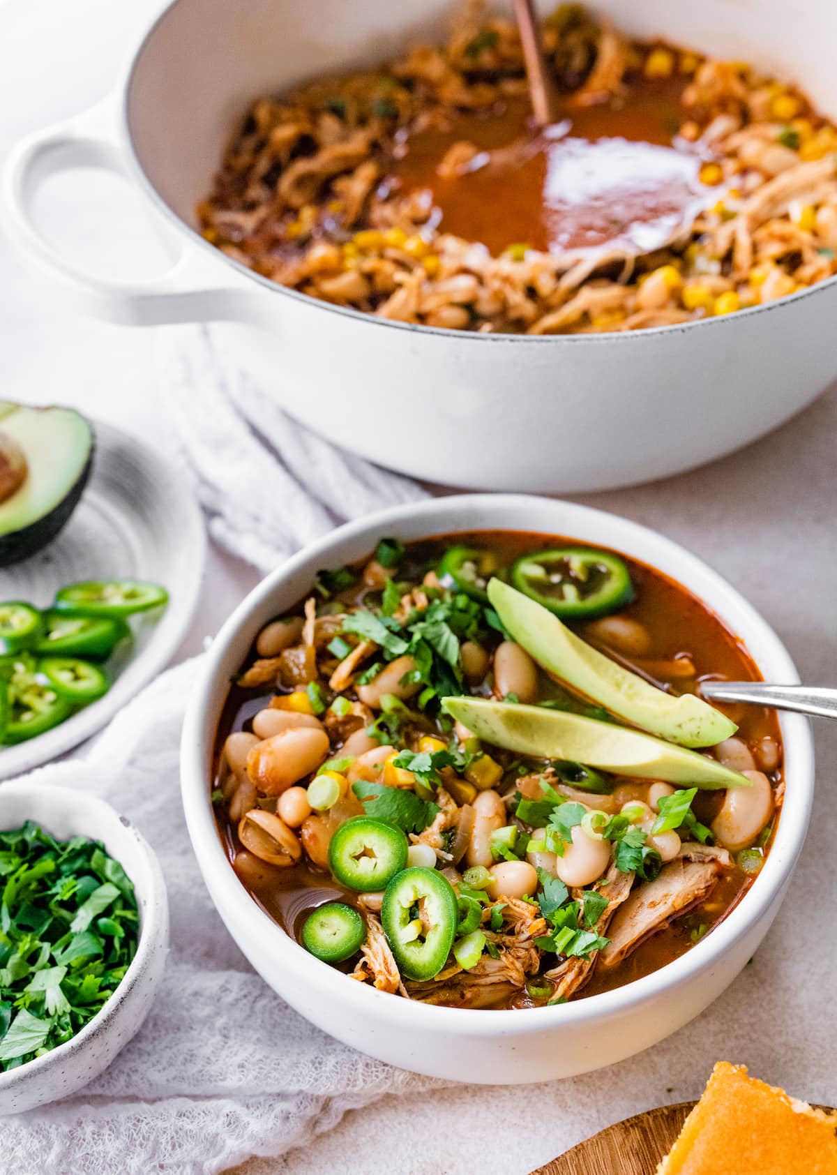 A bowl of white bean chicken chili next to a pot.