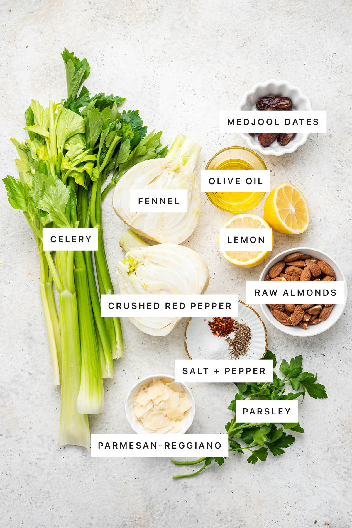 Ingredients measured out to make Fennel and Celery Salad: celery, fennel, olive oil, medjool dates, lemon, raw almonds, crushed red pepper, salt, pepper, parsley and parmesan-reggiano.