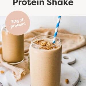 Peanut Butter Protein Shake topped with peanut butter, peanuts and a straw.