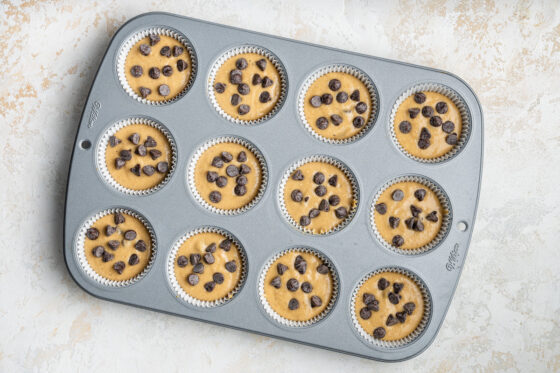 Mixture poured into a 12-muffin tin, topped with additional chocolate chips.