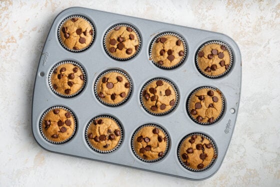 Twelve banana muffins in a muffin tin.