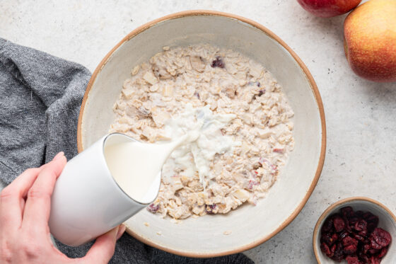 Bowl of bircher muesli with milk being poured on top.