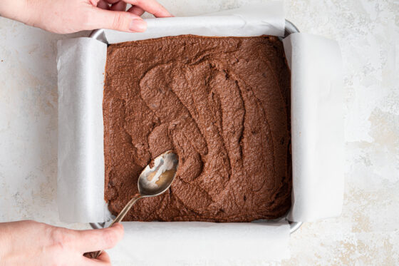 Brownie mixture smoothed into a square 8x8 lined baking dish.