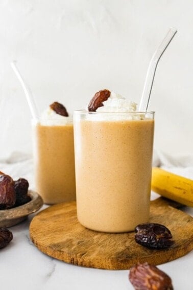 Two glasses of healthy date shake with a straw.