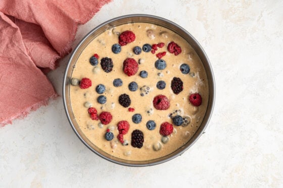Batter poured into a springform pan, topped with more berries.