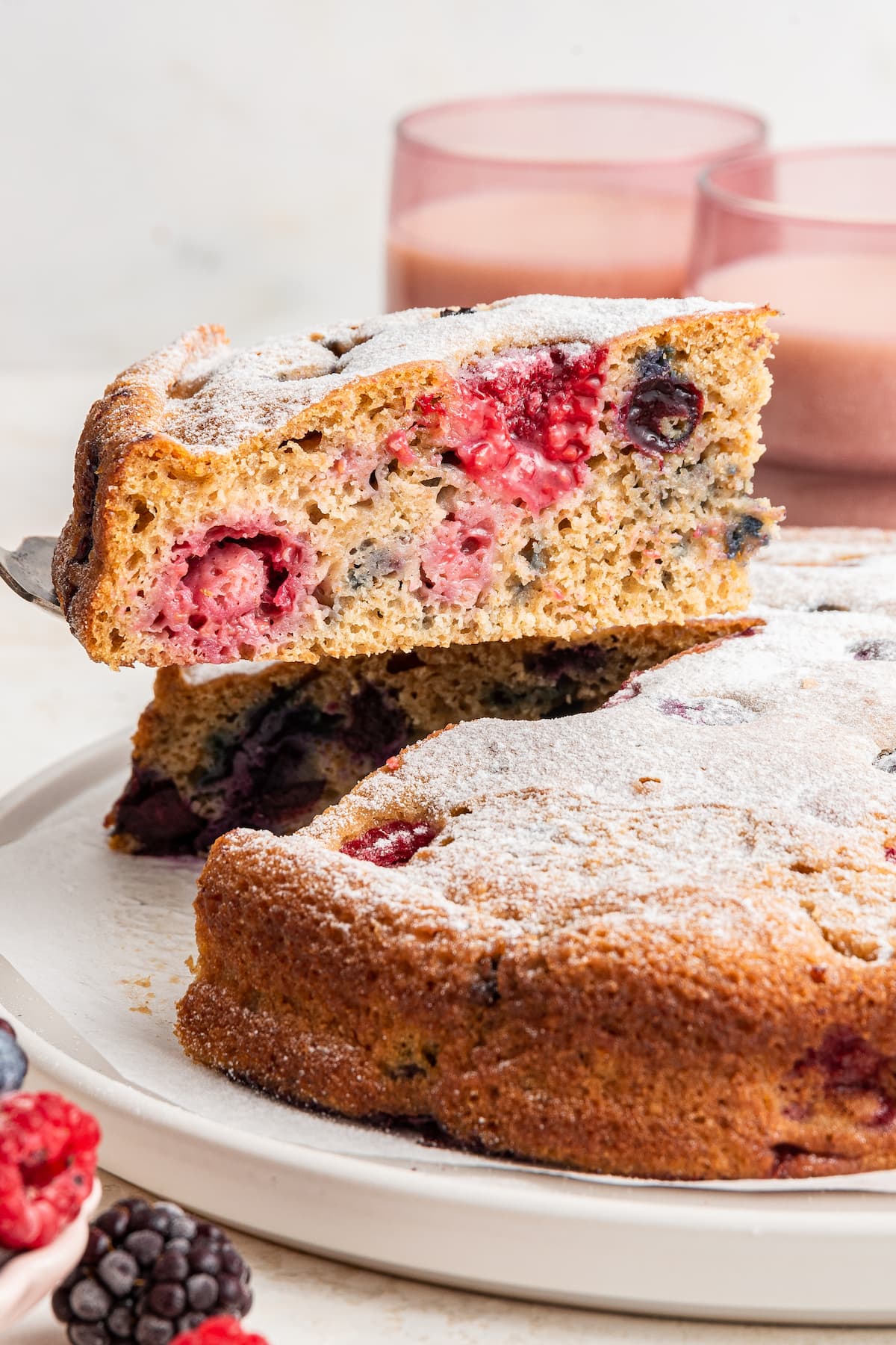 Removing a slice of easy berry cake from a plate.