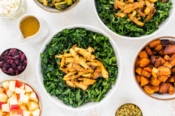 Building harvest bowls with a base layer of kale and topped with chicken.