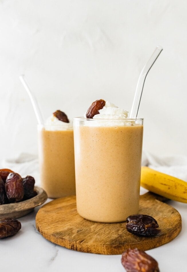 Two glasses of healthy date shake with a straw.