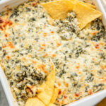 A dish of healthy spinach artichoke dip with chips.