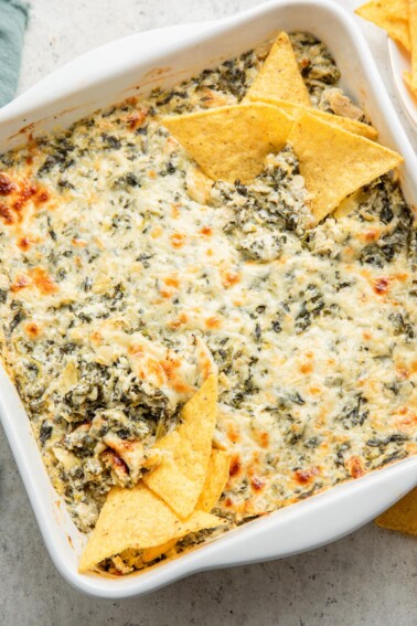 A dish of healthy spinach artichoke dip with chips.