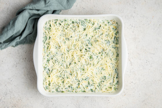 Spinach artichoke mixture pressed into prepared 8x8 dish, topped with more cheese.