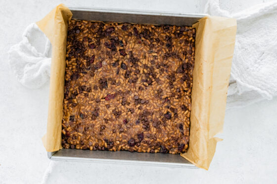 High fiber bar mixture pressed into an 8x8 pan lined with parchment paper.
