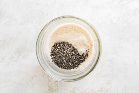 Chia seeds added to almond milk and protein powder in a jar.
