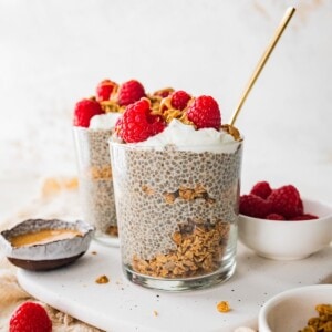 Protein chia pudding in a jar topped with fresh raspberries, greek yogurt and a drizzle of nut butter.