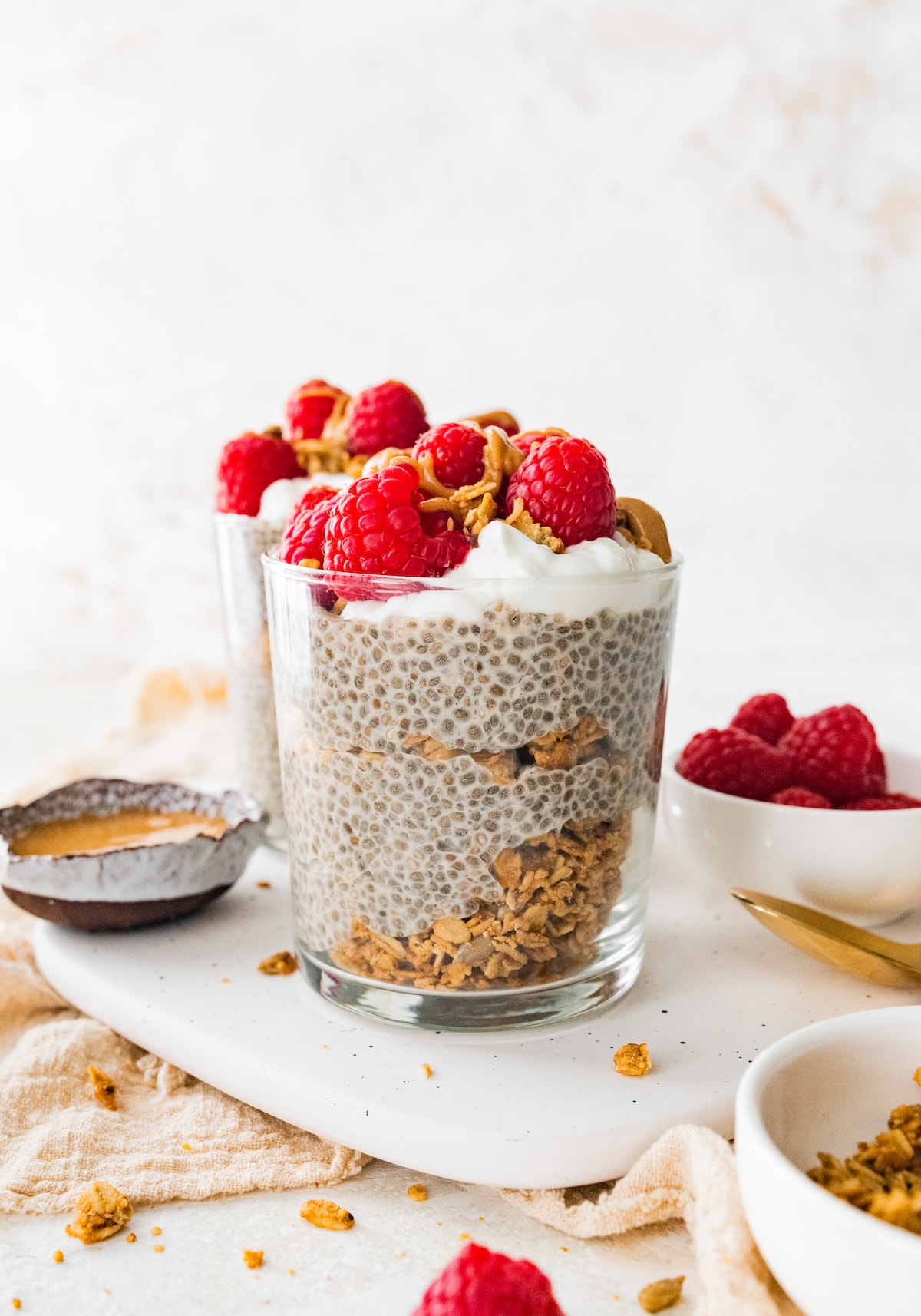 Protein chia pudding in a jar topped with fresh raspberries, greek yogurt and a drizzle of nut butter.