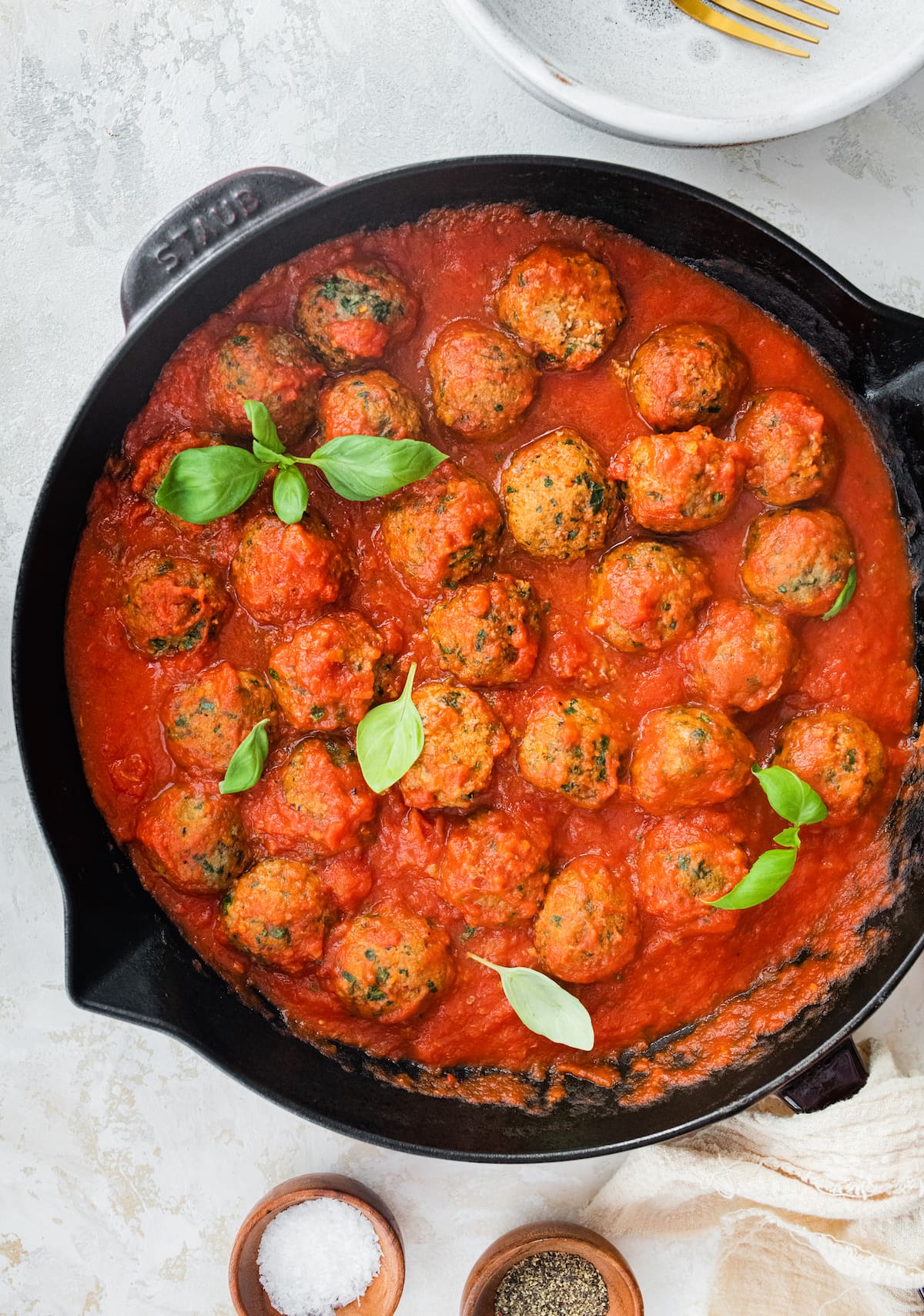 Spinach turkey meatballs with pasta sauce in a cast iron skillet.