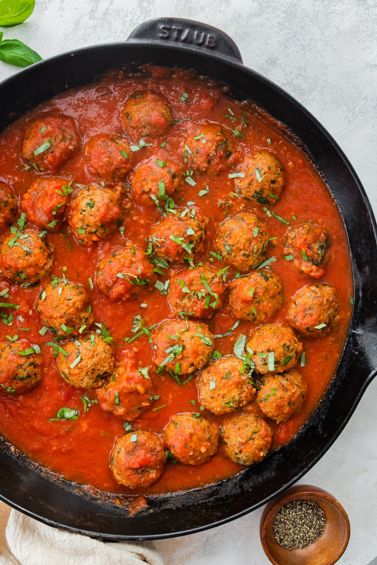 Spinach turkey meatballs with pasta sauce in a cast iron skillet.