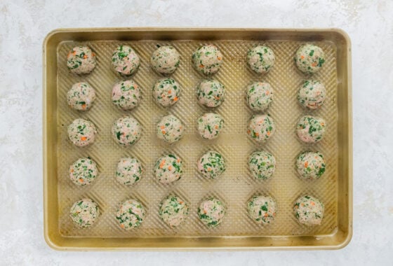 30 meatballs evenly spaced out on a baking sheet.