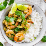 A bowl of thai green curry with shrimp and rice.