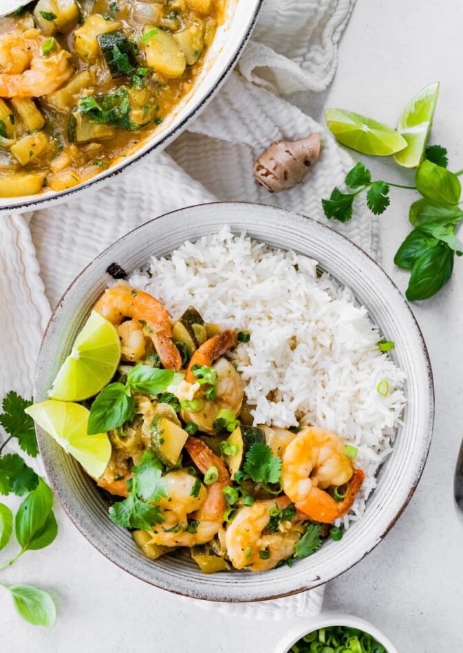 A bowl of thai green curry with shrimp served with rice.
