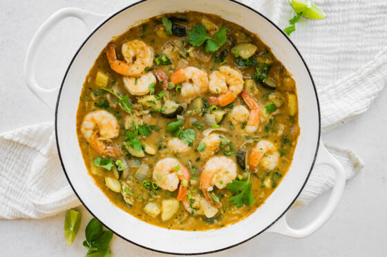 Thai green curry with shrimp in a pot with fresh herbs on top.