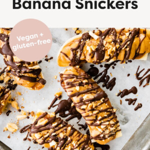 Frozen banana snickers on a baking tray with parchment paper.