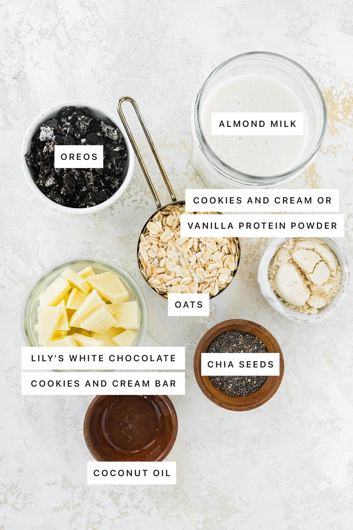 Ingredients measured out to make Cookies and Cream Overnight Oats: Oreos, almond milk, protein powder, oats, white chocolate, chia seeds and coconut oil.