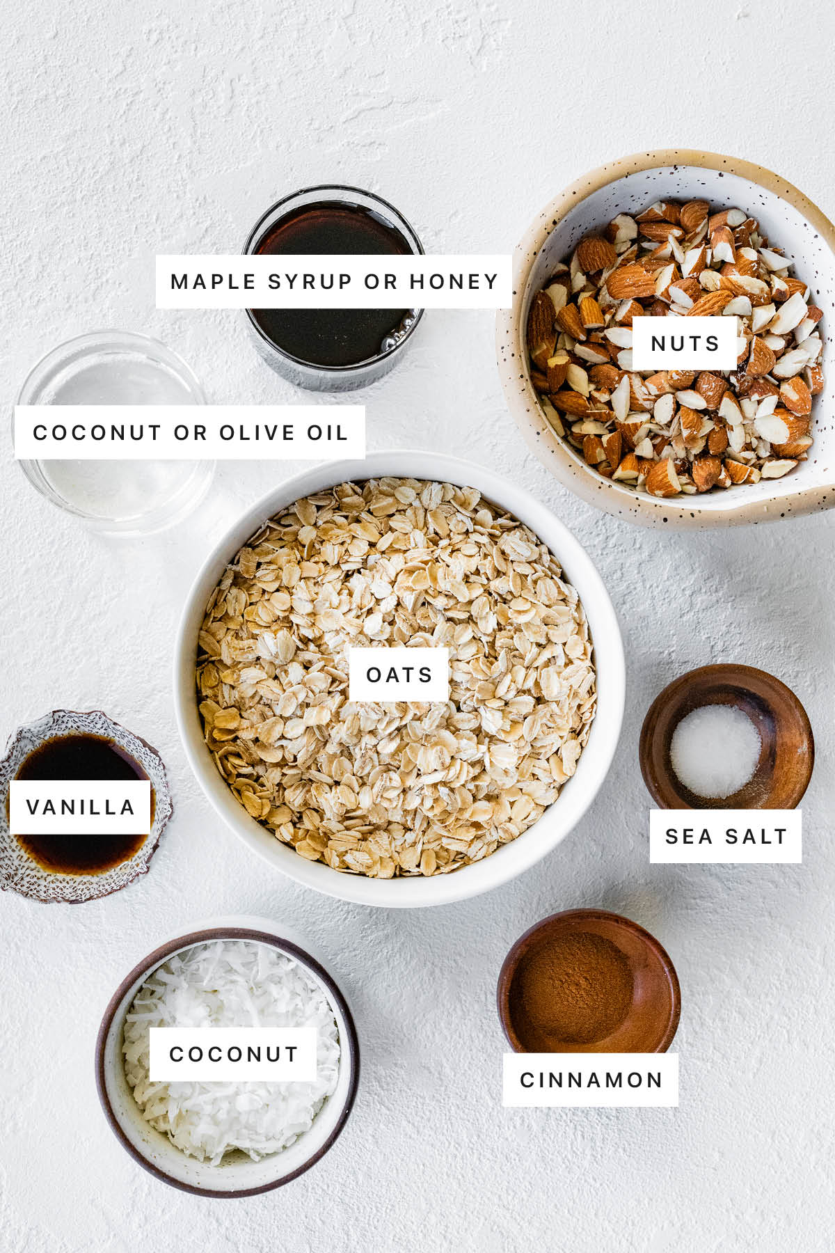 Ingredients measured out to make Granola Butter: maple syrup, nuts, coconut oil, oats, vanilla, sea salt, coconut and cinnamon.