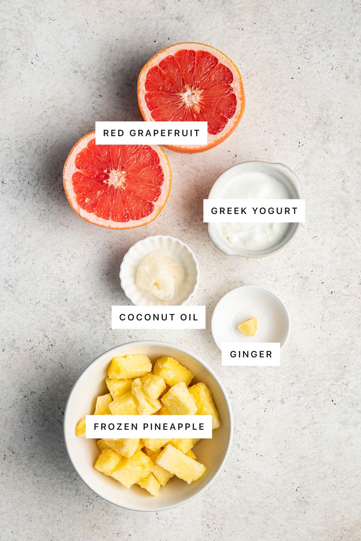 Ingredients measured out to make a Grapefruit Smoothie: red grapefruit, Greek yogurt, coconut oil, ginger and frozen pineapple.