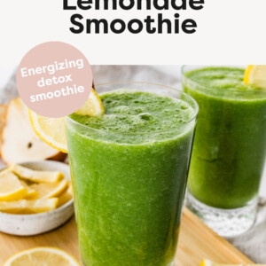 A green lemonade smoothie in a glass with a straw and fresh lemon slice.