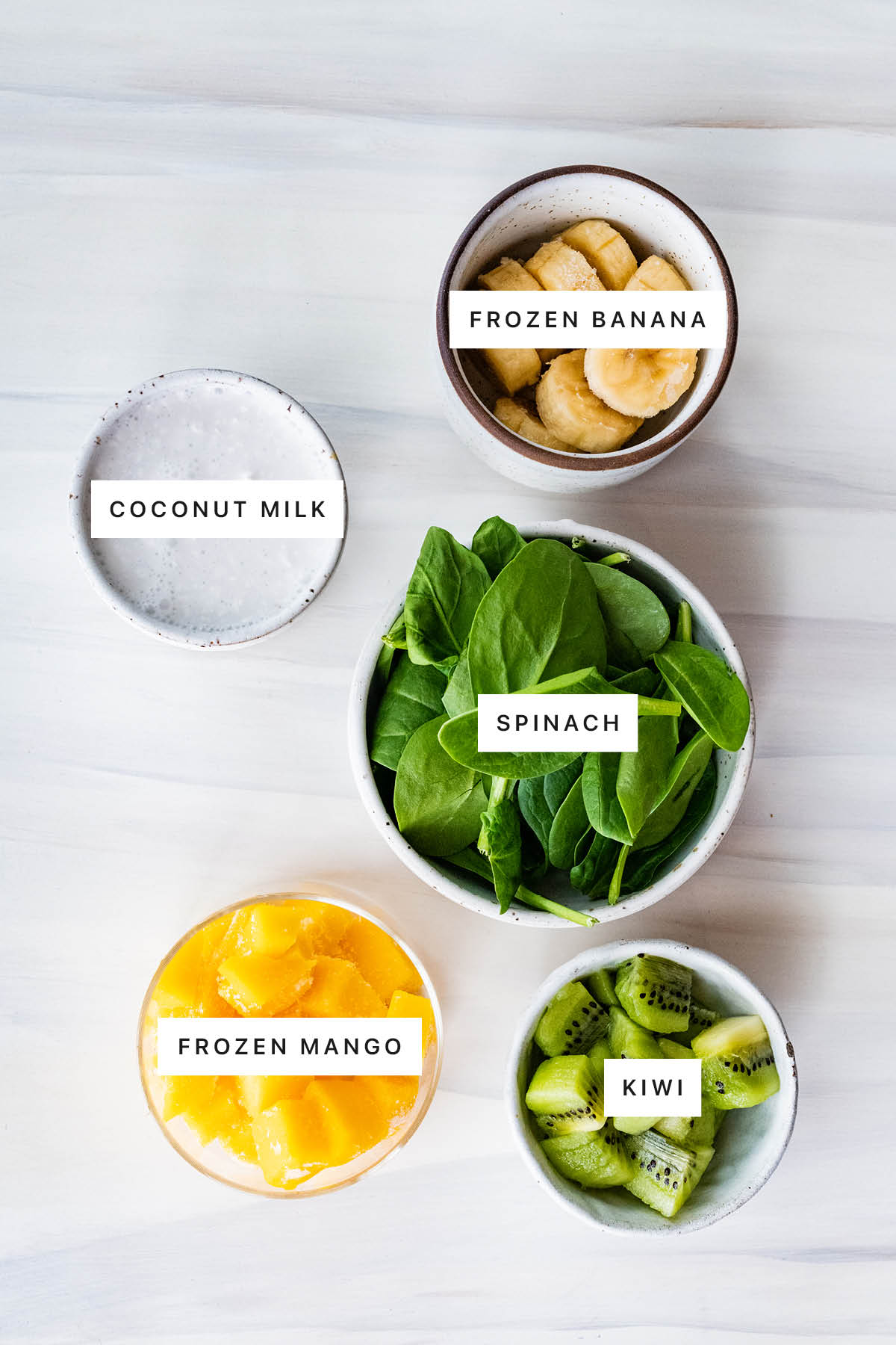 Measured ingredients to make a Kiwi Smoothie: frozen banana, coconut milk, spinach, frozen mango and kiwi.