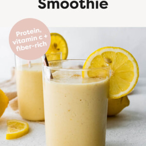 Two lemon smoothies with straws and fresh lemon slices.